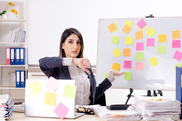 Young female employee in conflicting priorities concept 
