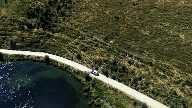 Cinematic 4k aerial drone footage driving next to the turquoise lake moke showcasing beautiful landscapes in the background in queenstown new zealand glenorchy road