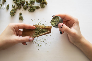 Woman preparing and rolling marijuana cannabis joint. Cannabis use concept. Woman rolling a...
