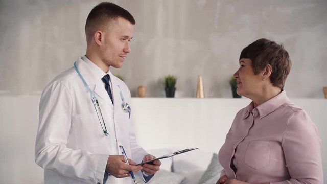 Doctor talking with his charming patient at her house