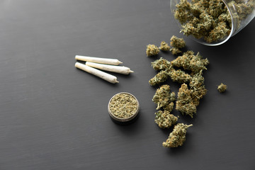 Cannabis buds on black table, grinder with fresh marijuana, close up, joint with weed,