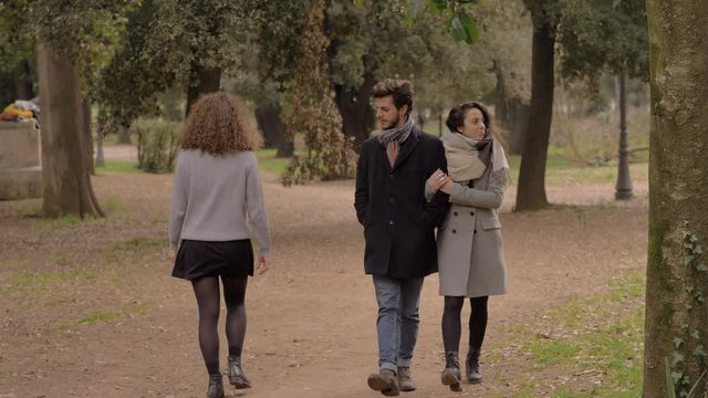 man walking with his girlfriend in the park and looks at other attractive woman