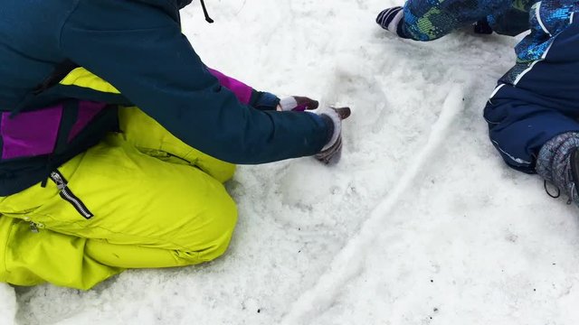 Kids playing with melting snow, making shapes of snow