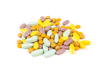 Pile of green orange purple and yellow pills over a white background