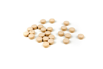 Scattered tan colored pills over a white background
