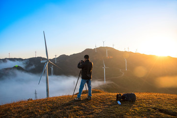 Photographers in the mountain wind turbines and sunrise and sunset cloud background