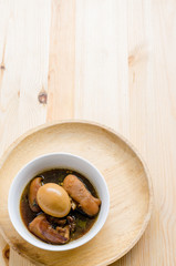 Egg and pork in brown sauce on wooden background, Thai Cuisine