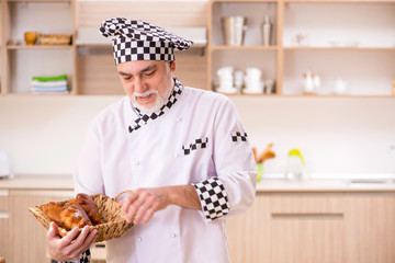 Old male baker working in the kitchen 