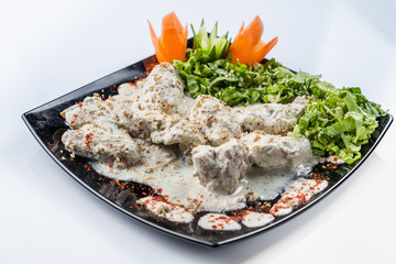 Gedlibzhe — kabardian chicken in sour cream sauce with onion garlic and spices in a frying pan close up