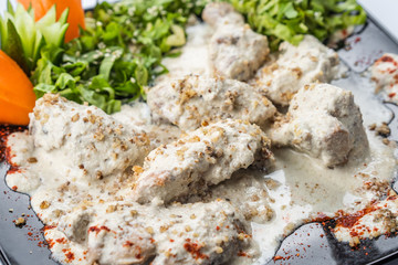 Gedlibzhe — kabardian chicken in sour cream sauce with onion garlic and spices in a frying pan close up