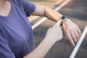 Women exercise in the morning using looking on her smart watches active sports activity on her hand.