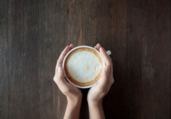 Female hands holding cups of coffee table background