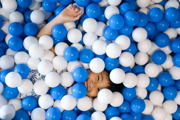 Little boy playing ball pool at playground