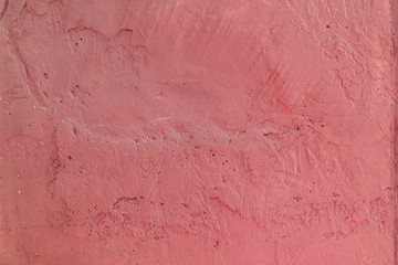 Blurred abstract background. The texture of a painted concrete rough surface with cracks and holes of an interesting pink color. Cropped shot, horizontal, place for text, nobody. The concept of repair