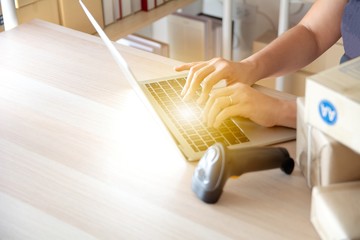 Courier scanning cardboard box with barcode scanner in warehouse. Close up of warehouse manager...