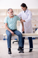 Fototapeta premium Old man visiting young male doctor 