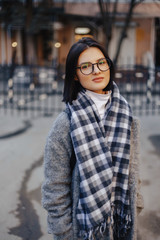 Attractive young girl wearing glasses in a coat walking on a sunny day