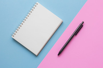 notebook and pen on pink and blue background