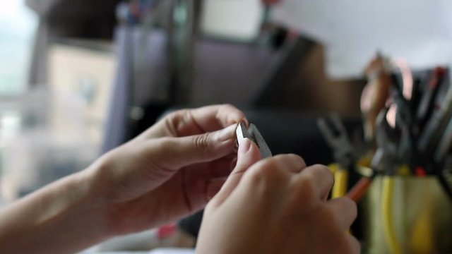 A hand using clamp to make accessories at her studio.