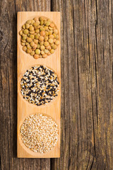 peeled and unpeeled sesame seeds, green lentils, old wooden table