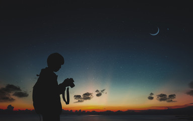 Silhouette of photographer standing in nature background with moon and night sky.