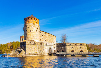 Fototapeta na wymiar Beautiful view of Olavinlinna, Olofsborg ancient fortress, the 15th-century medieval three - tower castle located in Savonlinna city on a sunny May day. lake Saimaa, Finland.