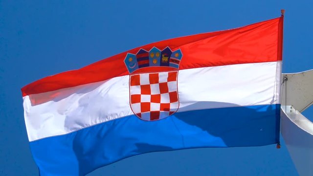 Croatia flag waving in the wind against blue sky in summer in harbor of Split old town in Croatia.