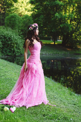 Cute woman in pink tulle dress in summer park