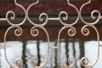 Wrought iron fence in the park Petergof. Background, water pond. Spring, sunny day.
