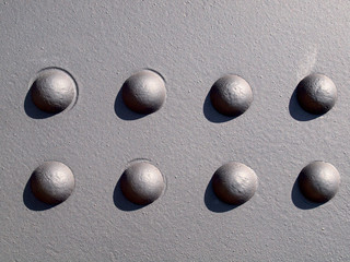 Detail of Black Metal wall with eight rivets