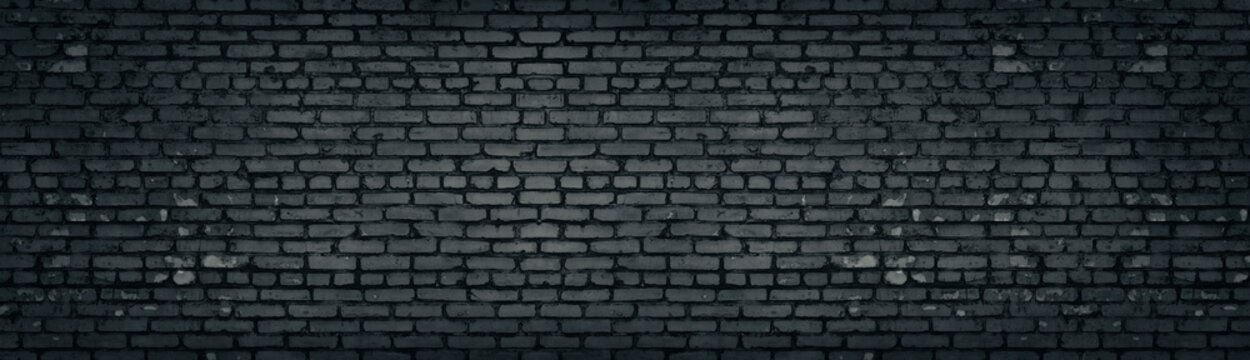 Wide old dark gray shabby brick wall texture. Black masonry panorama. Brickwork panoramic grunge background