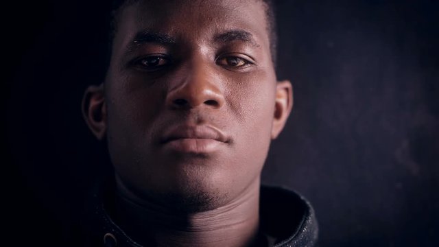 Confident serious black african man staring at camera in  the darkness