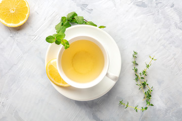 A cup of green tea with lemon, shot from the top with mint, thyme, and a place for text
