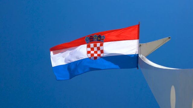 Croatia flag waving in the wind against blue sky in summer in harbor of Split old town in Croatia.