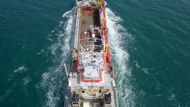 Red Hopper-Dredger ship roaring across the sea, Aerial follow footage.