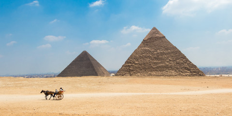 Fototapeta na wymiar Horse carriage with tourists in front of the Great Pyramids of Giza, Egypt