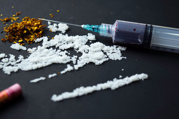 Cocaine and Indonesia rupiah ready for uses on dark table. Selective focus on syringe