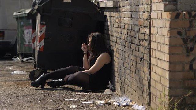 Drug,addiction.Desperate drug addict woman sitting alone in the street