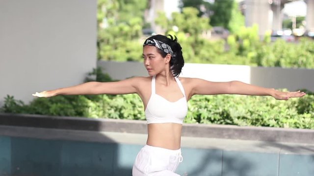 beautigul asian girl yoga and stretching outdoor with background city and swimming pool