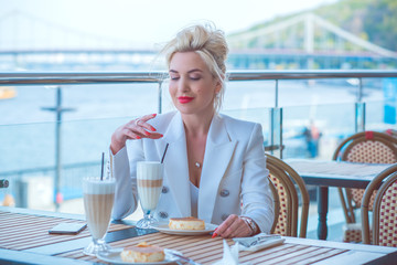 Luxurious woman in white jacket at restaurant. Lady with bright make up and red lips in European...