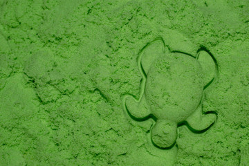 A pile of green kinetic sand for modeling and sculpted turtle.