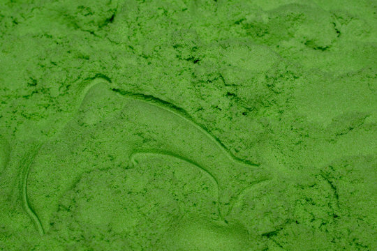 A pile of green kinetic sand for sculpting and sculpted dolphin