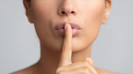 Women's secret. Woman holding finger on lips - obrazy, fototapety, plakaty
