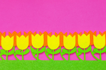 Abstract floral background of felt Easter tulip flowers of pink, purple and yellow on a plain background