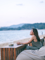 A beautiful asian woman enjoy sitting and relaxing on the beach by the seashore