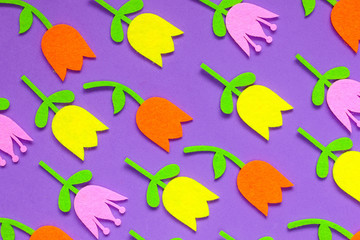 Abstract floral background of felt Easter tulip flowers of pink, purple and yellow on a plain background