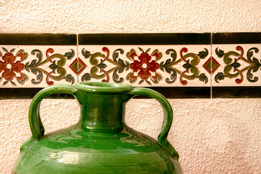 Decoraci&oacute;n r&uacute;stica con cenefas y un jarr&oacute;n de cer&aacute;mica verde.