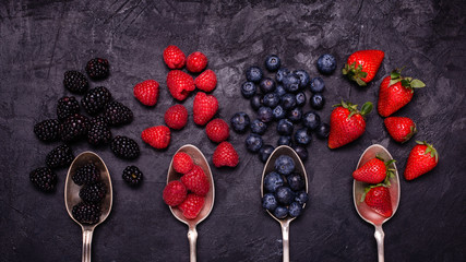 High-angle view in the foreground, in the rustic and dark background, variety of berries and...