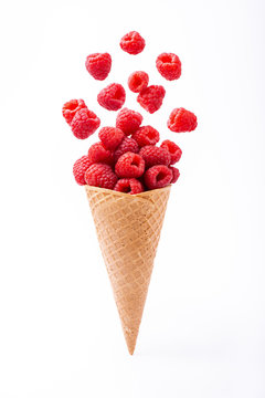In the foreground, cascade of fresh raspberries in the ice cream cone, isolated from the white background