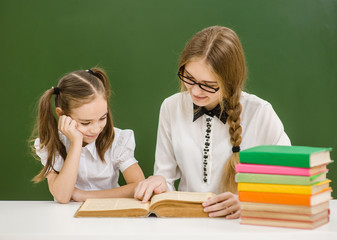 Teacher and little girl sitting in classroom together